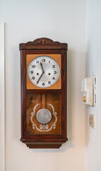 Grandfather Clock hung in the corner of the room with a old world fan regulator