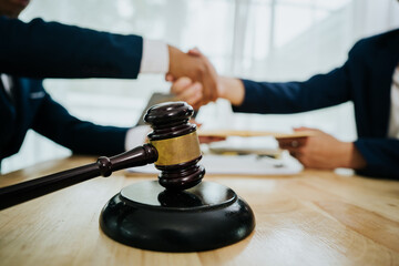 A lawyer consulting with a client in an office, reviewing legal documents and contracts related to...