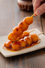 A close-up of traditional Japanese mitarashi dango&mdash;skewered rice dumplings grilled to perfection and coated with a glossy, sweet soy sauce glaze. The caramelized surface and rich glaze highlight the a