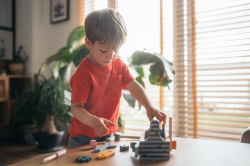 Little boy playing with wooden tools at home developing fine