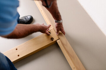 Unidentified retired man fixing screws to build wooden furniture