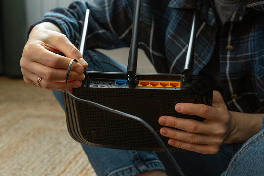 Technician connecting cable to wireless router for internet access