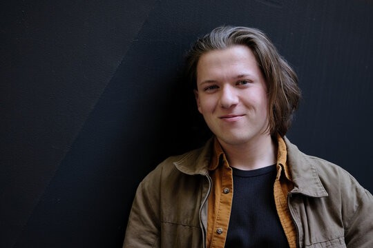 Young Individual in Casual Outfit Against a Textured Wall