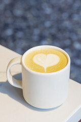 Warm cappuccino in a cup with heart-shaped latte art on top