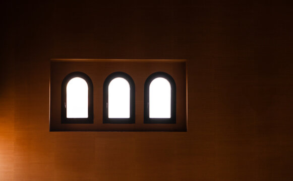Fototapeta Three arched windows illuminated against a dark wall