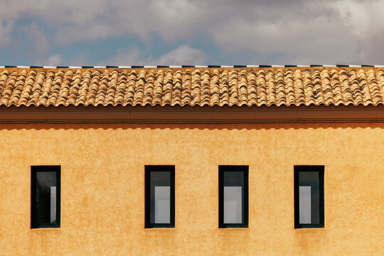 Terracotta facade with windows under a cloudy sky