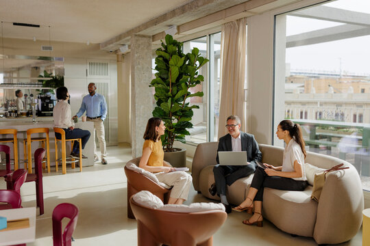Business people having informal meeting in modern office lounge