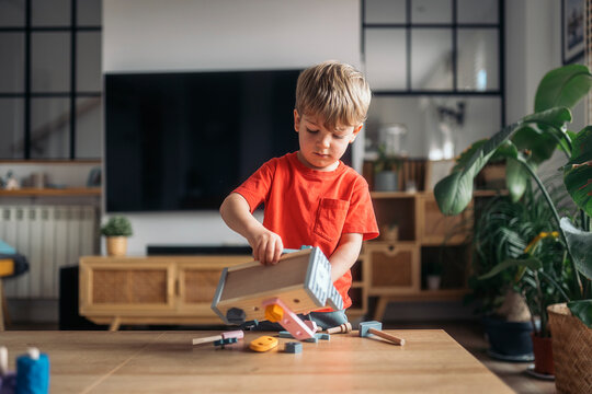 Naklejki Little boy playing with wooden educational toy tools at home