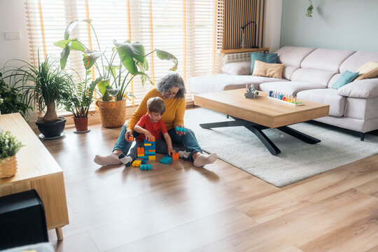 Grandmother and grandson playing with building blocks at home