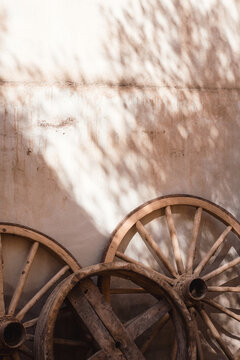Old wooden cartwheels leaning against a sunlit wall