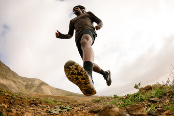 Wide shot from low angle of a runner crossing a rocky trail