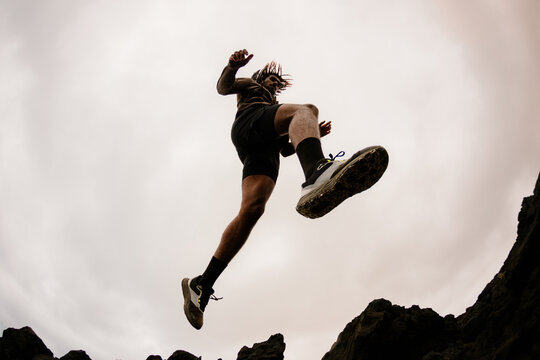 Person mid-air leaping between rocks, viewed from a low angle