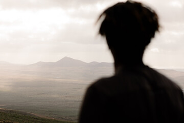 Volcanic mountains with the silhouette of a man gazing at horizon