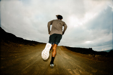 Flash-lit sports shot of the back of a professional trail runner