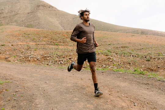 Trail runner sprints along a gravel path in the mountains