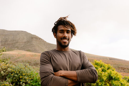 Athlete smiling, arms crossed with yellow-flowered bushes arround him
