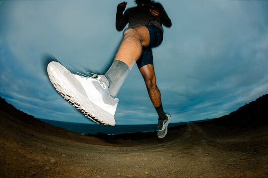 Flash-lit wide shot of a trail runner taking a long stride