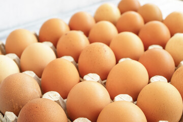 Brown chicken eggs in a cardboard tray on a rustic wood background for farm and food concepts and healthy eating or cooking recipes and ingredients advertising.