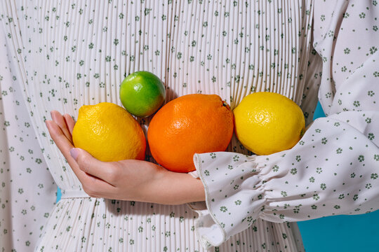 Fresh Citrus Fruits Held Against a Floral Patterned Dress