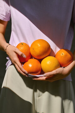 Bright, vibrant oranges cradled in hands convey freshness