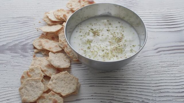 diet chips and hummus dip in metal bowl on white wooden background in close-up