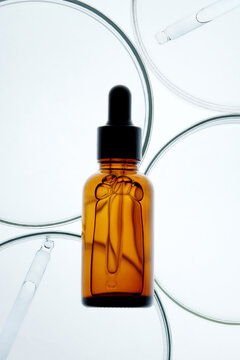 Amber glass dropper bottle with face serum and Petri dishes.