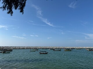 Scenic Coastal View with Gentle Waves and Fishing Boats in Harbor