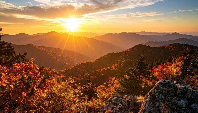 Majestic sunset over layered mountains with colorful autumn foliage and warm golden light illuminating the landscape