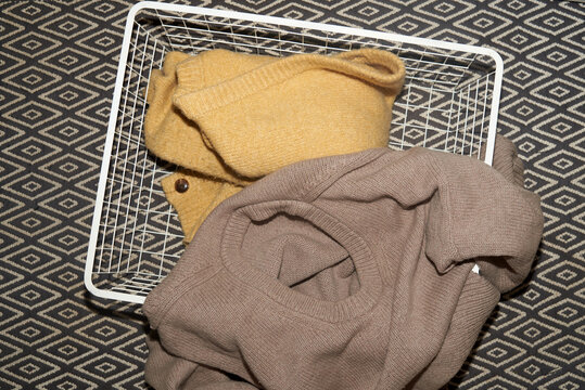 Cozy sweaters lying in a white wire basket