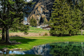 Alpine lake Gover surrounded by green trees as a mountain with a waterfall in the background in Gressoney Saint Jean, Italy.