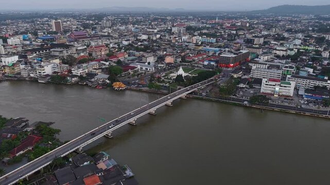 Aerial view of Surat Thani, Thailand, featuring the City Pillar Shrine, Tapi River, and city bridges under a vast sky at dusk.