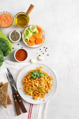 Red lentil dish with leek and carrot on the plate with ingredients nearby. Vegetarian cooking, top view, copy space