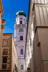 St. Stephans cathedral in Passau, Germany is an old white church with green metal domes on top of...