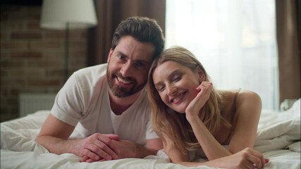 Carefree family glad Caucasian couple relaxing in bed looking at camera in bedroom pair wife husband lying cozy morning tenderness married woman man enjoying closeness warm bedding comfort affection - Powered by Adobe