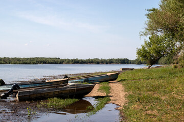 Serene riverside view featuring old boats resting on the shore, surrounded by lush greenery. A tranquil setting perfect for nature lovers, outdoor enthusiasts and fishing.
rustic-river-boats-nature
