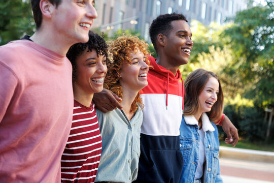 Happy students walking together on campus smiling and laughing