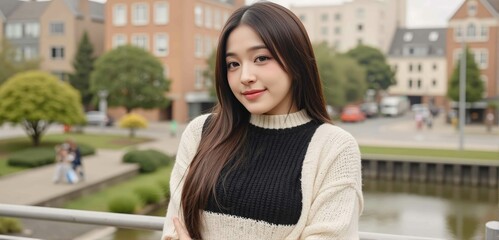 Stylish young woman with messy top knot bun wears cropped sweater and denim skirt smiling in downtown park unique low-angle stock photo