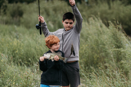 Brothers fishing together holding up their freshwater catch