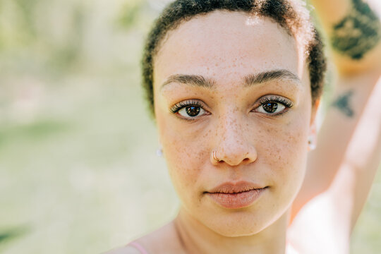 Freckled woman looks forward with soft focus and green backdrop