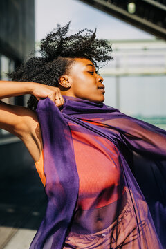 Close-up of woman wrapped in purple fabric with windswept hair