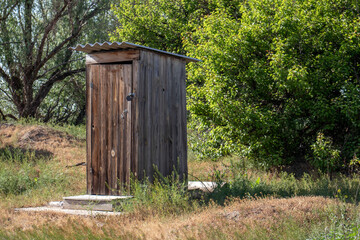 Rustic wooden outdoor toilet in a rural setting surrounded by green trees and dry grass, showcasing traditional countryside lifestyle in Russia.
rustic-wooden-outdoor-toilet-rural-russia