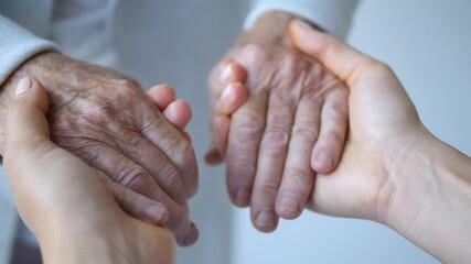 Young woman gently holding wrinkled hands of elderly person, providing compassionate support and connection against light gray background - Powered by Adobe