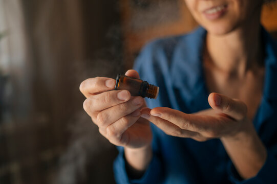 Woman using essential oil for aromatherapy at home