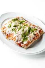 A rectangular slice of pizza with melted cheese, green pesto sauce, and herbs on a white plate, isolated on a clean background. Crispy crust and vibrant toppings make it an appetizing dish