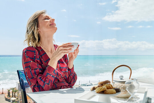 Woman enjoying herbal tea by the sea on a sunny day