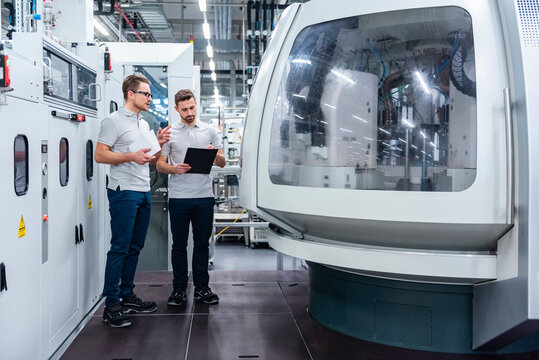 Employees discussing in a production hall with machinery
