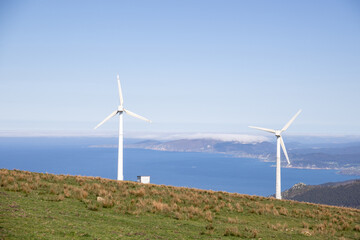Wind turbines rise over grazing cows in Meizoso, Galicia, Spain — a peaceful harmony between...