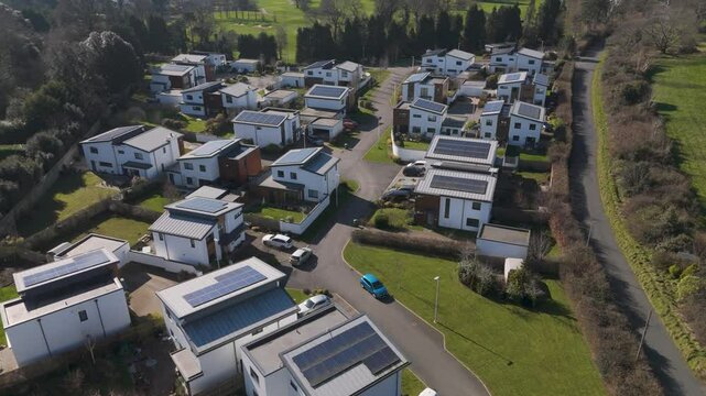 Aerial view of tree-bordered community of detached and semi-detached solar homes with curved roads and generous spacing promoting relaxed green living