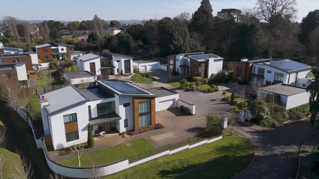 Aerial of looping tree-lined roads flanked by evenly spaced solar homes with private lawns and driveways demonstrating ordered green masterplan