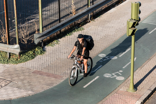 Young female frontline worker riding cycle at signal on sunny day